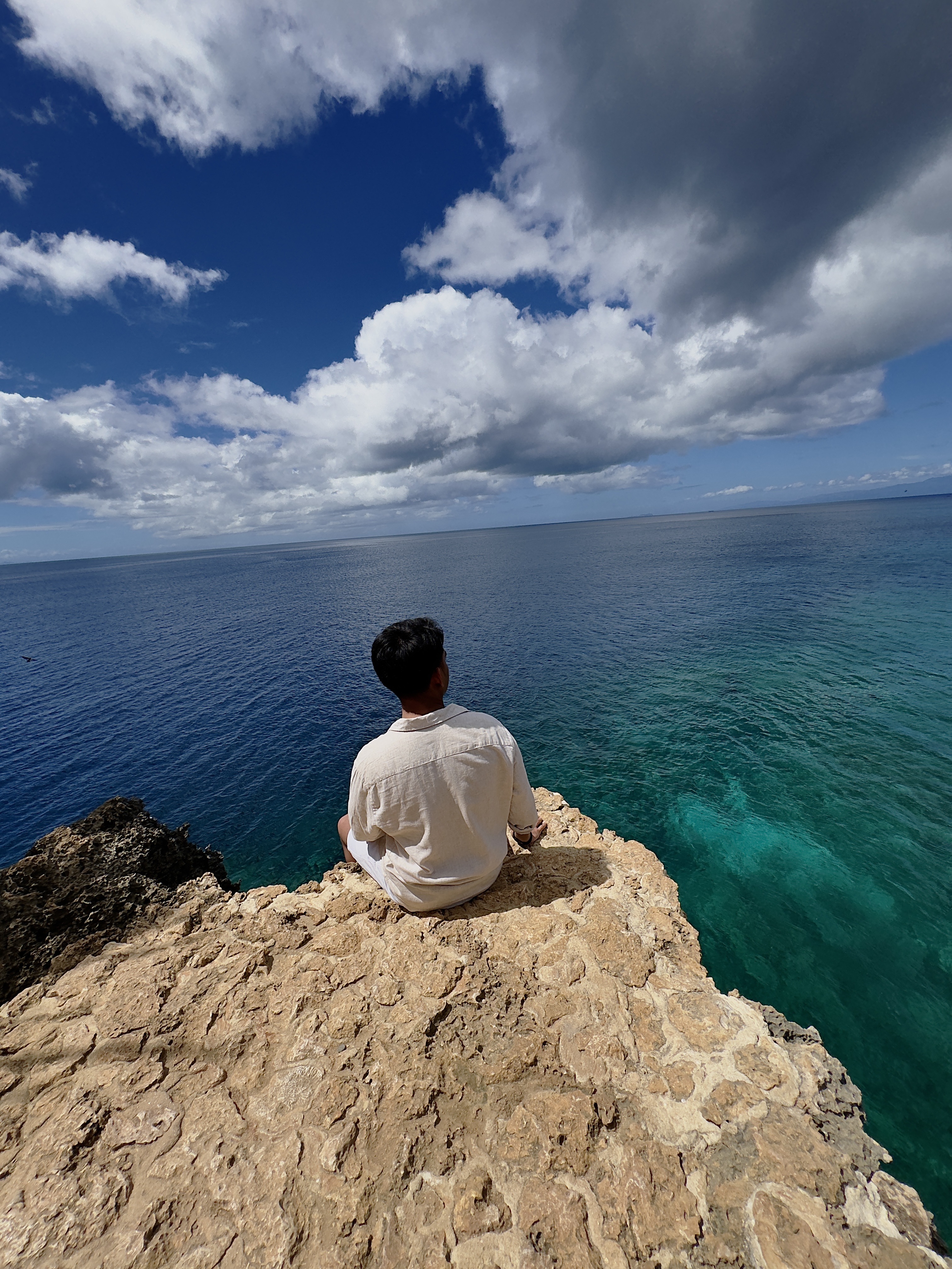 Froyows seated by the Pitogo cliff looking at the blue horizon, the crystal clear waters of Siquijor