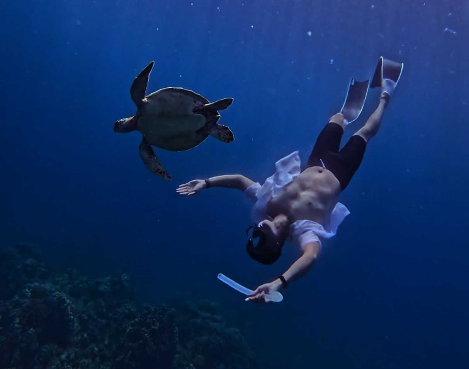 Froyows freediving with a sea turtle wearing long fins