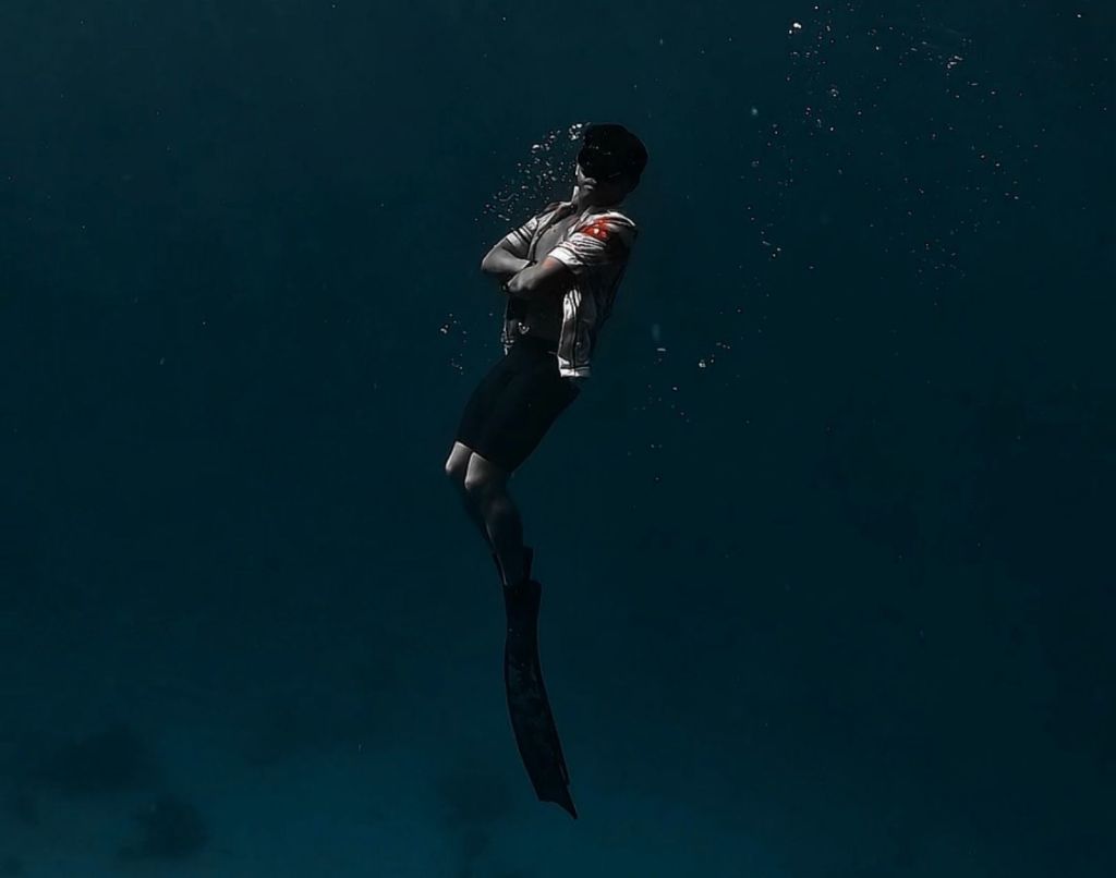 Froyows Travel & Freediving founder posing relaxed underwater demonstrating safety freediving in his iconic open polo outfit against the blue water of Siquijor
